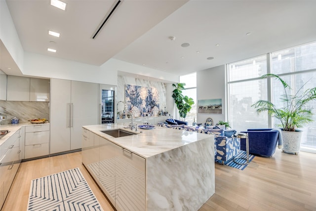 1918 Olive St Unit 502, Dallas, TX 75201 - kitchen with modern cabinets, light wood-style flooring, backsplash, light stone counters, and a wall of windows