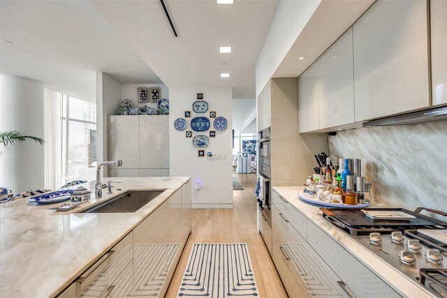 1918 Olive St Unit 502, Dallas, TX 75201 - kitchen with modern cabinets, light wood finished floors, appliances with stainless steel finishes, light stone counters, and white cabinets