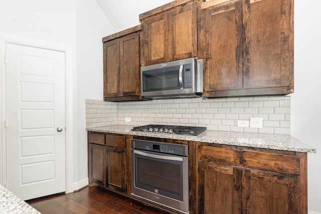 937 Nathanael Greene Ct, Aubrey, TX 76227 - kitchen featuring appliances with stainless steel finishes, decorative backsplash, dark wood finished floors, light stone counters, and lofted ceiling