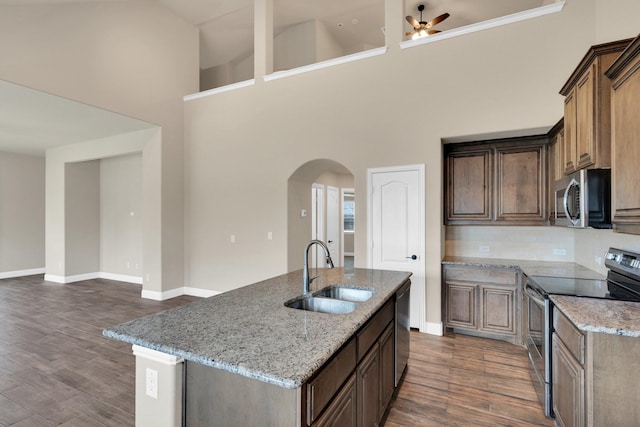 350 Windsor St, Waxahachie, TX 75165 - kitchen featuring stainless steel appliances, arched walkways, light stone counters, dark wood-style floors, and a high ceiling
