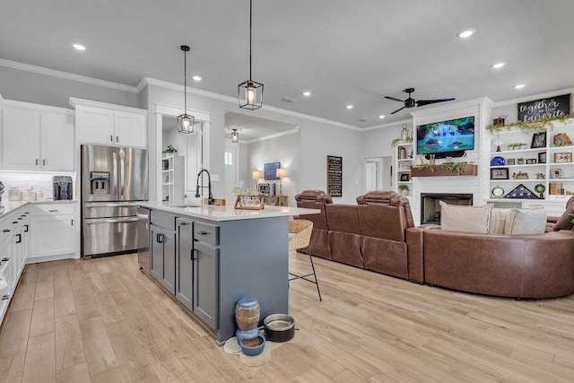 14423 Woodland Crk, Tyler, TX 75706 - kitchen with appliances with stainless steel finishes, ceiling fan, light wood-type flooring, open floor plan, and ornamental molding