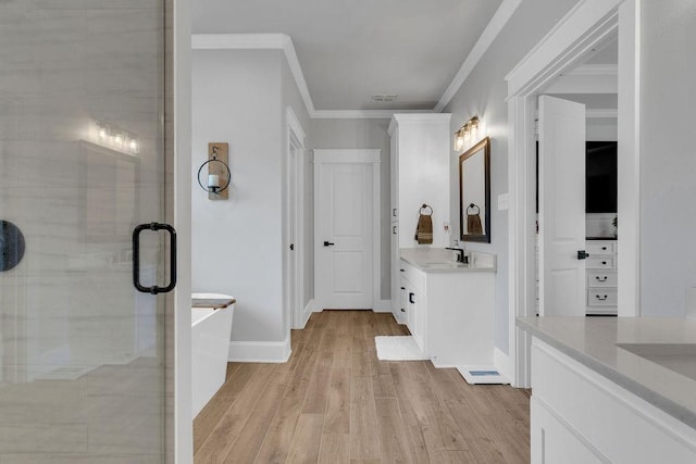 14423 Woodland Crk, Tyler, TX 75706 - bathroom featuring two vanities, wood finished floors, a shower stall, crown molding, and a freestanding bath