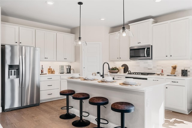 3926 Lupine Trl, Midlothian, TX 76065 - kitchen with appliances with stainless steel finishes, decorative backsplash, light wood finished floors, a kitchen bar, and light countertops