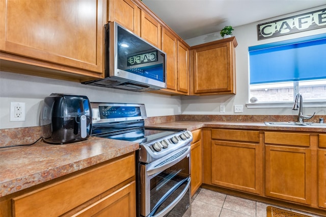 113 Cayman Dr, Lancaster, TX 75146 - kitchen featuring stainless steel appliances, light tile patterned floors, and brown cabinets
