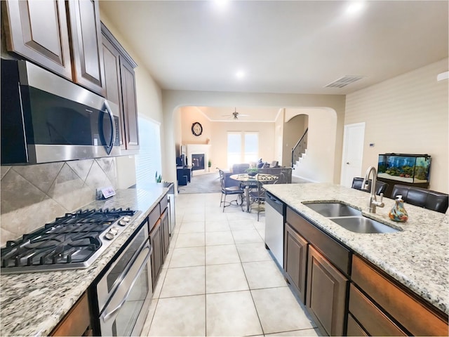 3812 Gennaker Dr, Denton, TX 76210 - kitchen featuring stainless steel appliances, arched walkways, open floor plan, ceiling fan, and tasteful backsplash