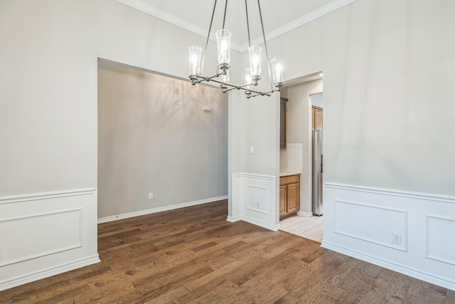 4471 Chandler Dr, Frisco, TX 75034 - unfurnished dining area featuring a chandelier, crown molding, light wood finished floors, a decorative wall, and a wainscoted wall