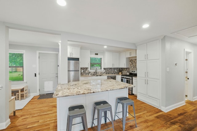 3000 Binyon St, Fort Worth, TX 76133 - kitchen featuring appliances with stainless steel finishes, a breakfast bar, light wood-style flooring, white cabinets, and recessed lighting