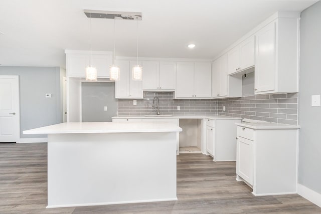 3828 Pacesetter Dr, Dallas, TX 75241 - kitchen featuring a center island, tasteful backsplash, wood finished floors, white cabinets, and recessed lighting