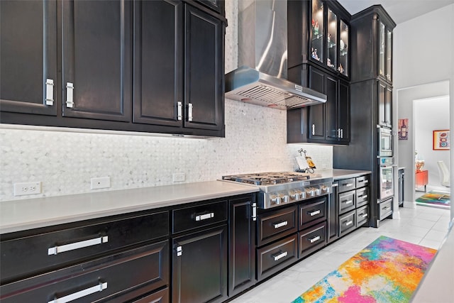 1833 Rolling Heights Ln, Fort Worth, TX 76008 - kitchen featuring wall chimney exhaust hood, appliances with stainless steel finishes, dark cabinets, decorative backsplash, and light countertops