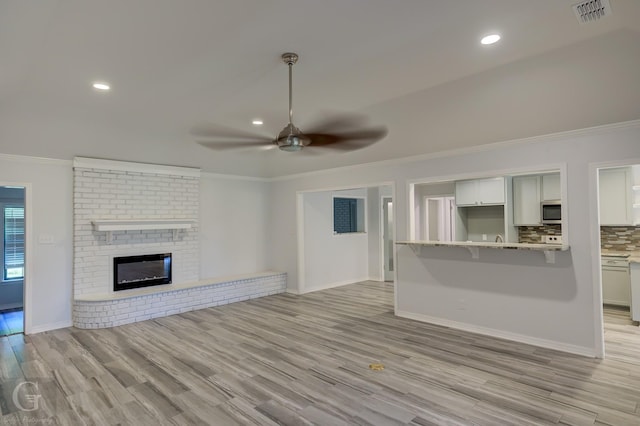 163 Sistrunk Ln, Bossier City, LA 71112 - unfurnished living room with ornamental molding, a ceiling fan, light wood-style flooring, recessed lighting, and a brick fireplace