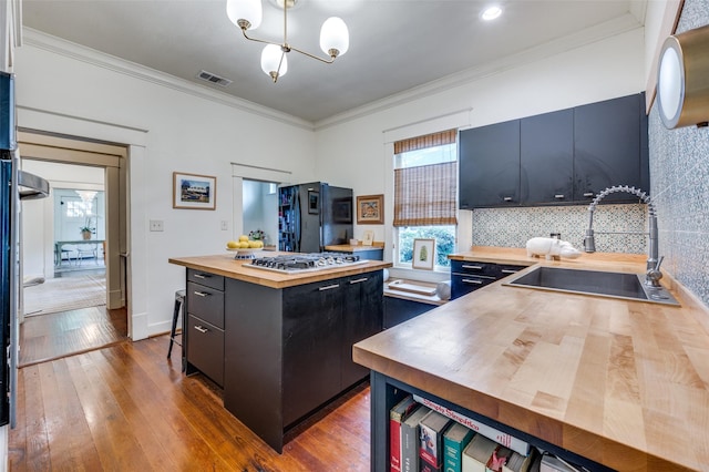 5818 Worth St, Dallas, TX 75214 - kitchen featuring butcher block counters, dark cabinets, stainless steel gas cooktop, freestanding refrigerator, and ornamental molding