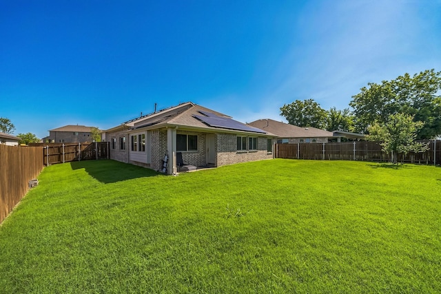 2806 Ocean Dr, Lancaster, TX 75146 - back of house with a fenced backyard, brick siding, roof mounted solar panels, and roof with shingles