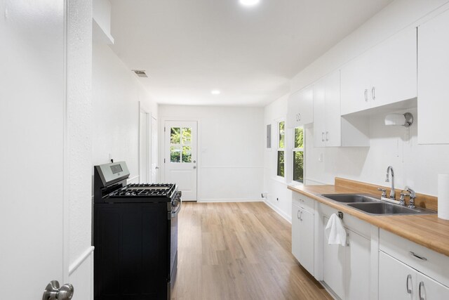 1308 Edgecliff Rd, Fort Worth, TX 76134 - kitchen featuring stainless steel range with gas stovetop, light wood finished floors, healthy amount of natural light, white cabinetry, and recessed lighting