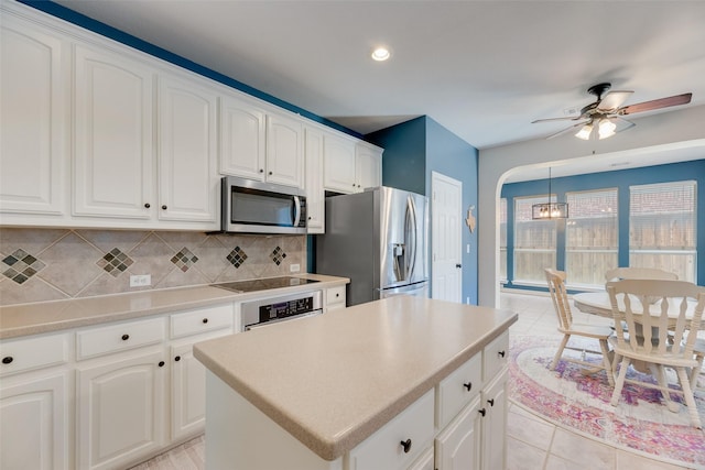 2621 Princeton Dr, Flower Mound, TX 75022 - kitchen with appliances with stainless steel finishes, decorative backsplash, a ceiling fan, a center island, and white cabinets