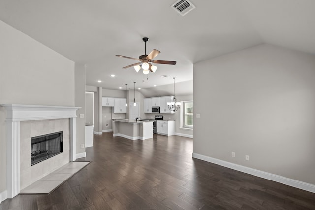 6001 Harwich Ln, Fort Worth, TX 76179 - unfurnished living room with ceiling fan, dark wood-style floors, a fireplace, a chandelier, and vaulted ceiling