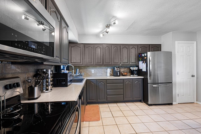 9395 Green Springs Cir, Sanger, TX 76266 - kitchen with appliances with stainless steel finishes, decorative backsplash, light countertops, light tile patterned floors, and a textured ceiling