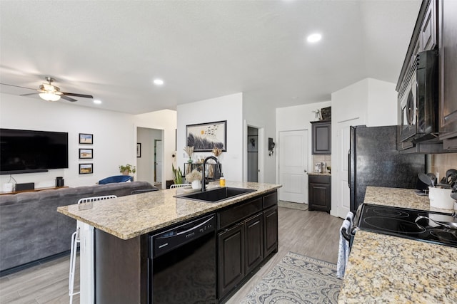 100 Tall Meadow St, Azle, TX 76020 - kitchen with black appliances, an island with sink, light wood finished floors, ceiling fan, and open floor plan