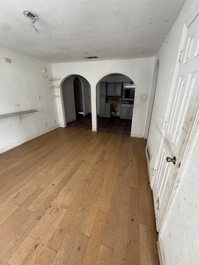 1421 Richard St, Mesquite, TX 75149 - spare room featuring wood-type flooring, arched walkways, and a textured ceiling
