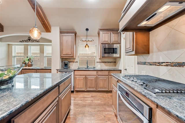 5005 Parkplace Dr, Denton, TX 76226 - kitchen featuring stainless steel appliances, range hood, tasteful backsplash, dark stone countertops, and hanging light fixtures