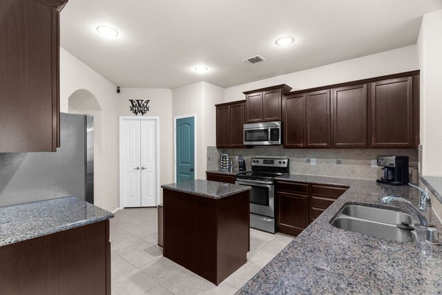 1104 Cheyenne Dr, Aubrey, TX 76227 - kitchen featuring stainless steel appliances, a center island, arched walkways, tasteful backsplash, and dark brown cabinetry