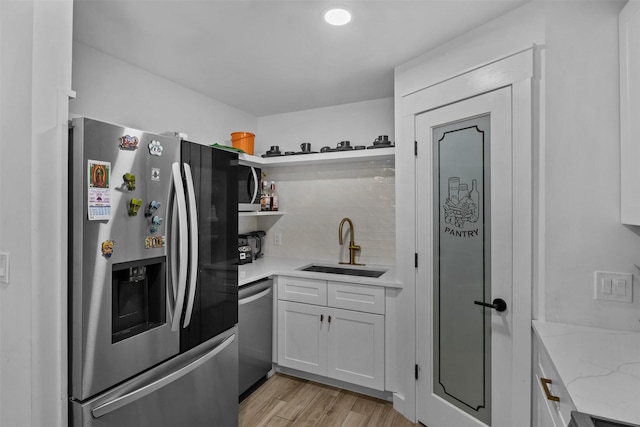 2304 Spanish Trl, Irving, TX 75060 - kitchen featuring appliances with stainless steel finishes, open shelves, light wood-type flooring, light stone counters, and white cabinets