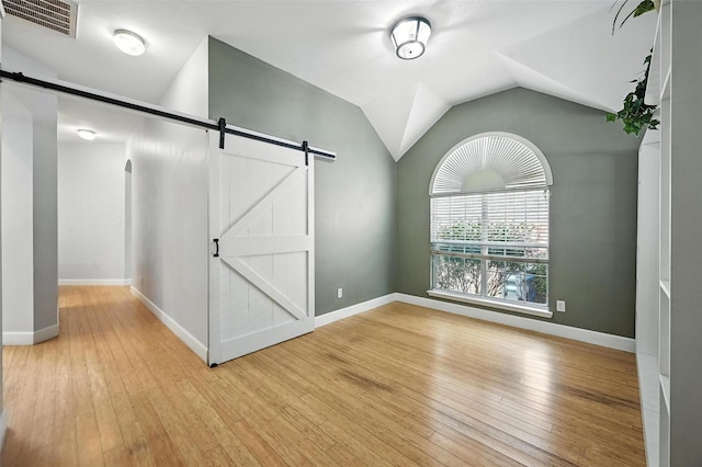 4917 Summer Oaks Ln, Fort Worth, TX 76123 - empty room featuring a barn door, hardwood / wood-style floors, and vaulted ceiling