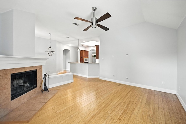 4917 Summer Oaks Ln, Fort Worth, TX 76123 - unfurnished living room featuring arched walkways, ceiling fan, light wood-style floors, a tile fireplace, and vaulted ceiling