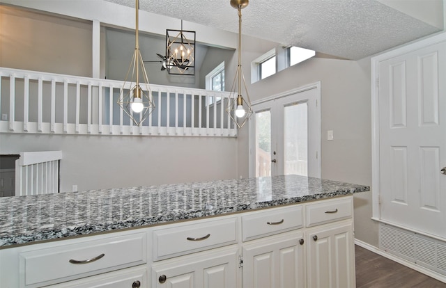 4300 Hidden Creek Dr, Arlington, TX 76016 - kitchen with dark stone countertops, a chandelier, white cabinetry, dark wood-type flooring, and a textured ceiling