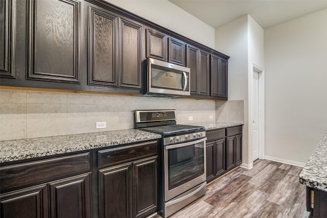 1304 Meridian Dr, Forney, TX 75126 - kitchen featuring stainless steel appliances, wood finished floors, tasteful backsplash, dark brown cabinetry, and light stone countertops