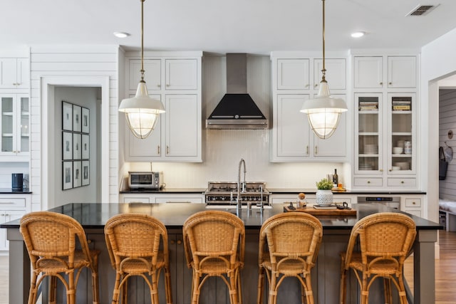 4705 Clydesdale Dr, Flower Mound, TX 75028 - kitchen with wall chimney exhaust hood, dark countertops, a breakfast bar area, glass insert cabinets, and pendant lighting