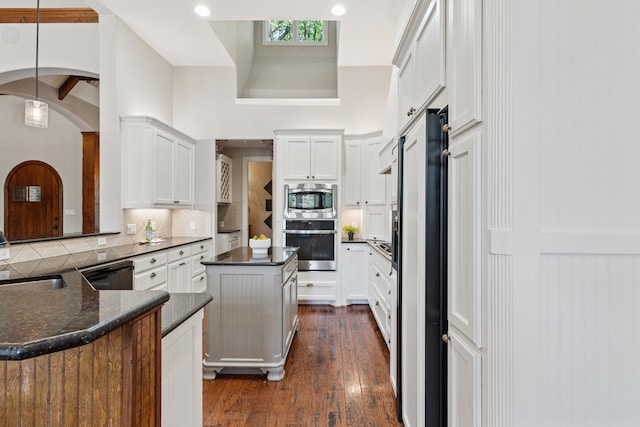 105 Blue Sage Ct, Weatherford, TX 76087 - kitchen with stainless steel appliances, tasteful backsplash, white cabinetry, arched walkways, and dark wood-style floors
