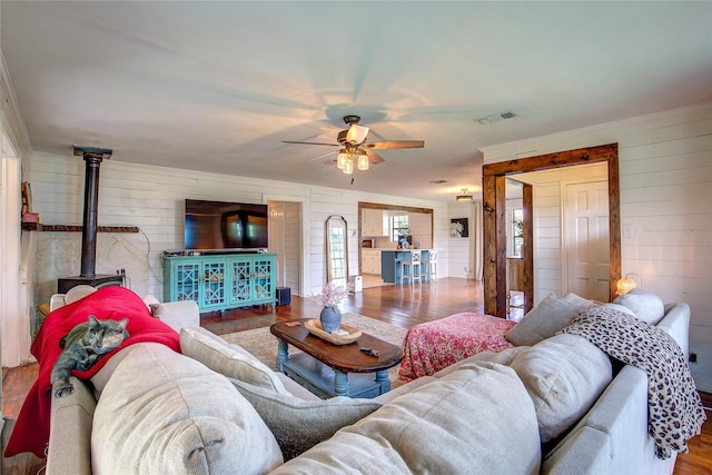 929 Church St, Sulphur Springs, TX 75482 - living area with wood finished floors, wooden walls, a wood stove, and a ceiling fan