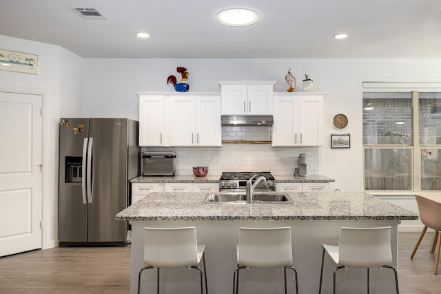9657 Alderleaf Trl, Fort Worth, TX 76036 - kitchen featuring stainless steel appliances, under cabinet range hood, white cabinetry, tasteful backsplash, and light wood-type flooring
