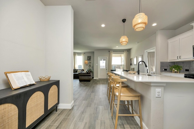 2305 Waggoner Ranch Dr, Weatherford, TX 76087 - kitchen featuring recessed lighting, white cabinetry, a breakfast bar, light countertops, and light wood-style floors