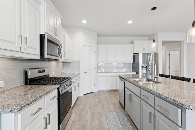 1000 Napier Way, Fort Worth, TX 76247 - kitchen with stainless steel appliances, white cabinetry, backsplash, light wood-style flooring, and an island with sink