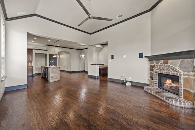 682 Cannon Dr, Fate, TX 75087 - unfurnished living room featuring ceiling fan, high vaulted ceiling, a fireplace, crown molding, and dark wood-type flooring