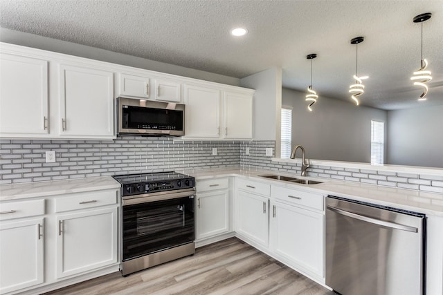 8732 Hunters Trl, Fort Worth, TX 76123 - kitchen featuring appliances with stainless steel finishes, a textured ceiling, white cabinets, backsplash, and hanging light fixtures