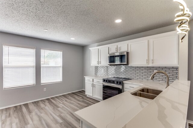 8732 Hunters Trl, Fort Worth, TX 76123 - kitchen with appliances with stainless steel finishes, a textured ceiling, light wood-style floors, tasteful backsplash, and white cabinetry