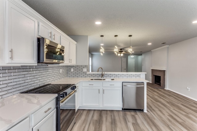 8732 Hunters Trl, Fort Worth, TX 76123 - kitchen with appliances with stainless steel finishes, a peninsula, ceiling fan, tasteful backsplash, and white cabinetry