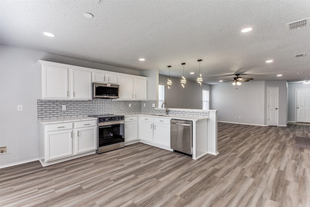 8732 Hunters Trl, Fort Worth, TX 76123 - kitchen featuring appliances with stainless steel finishes, ceiling fan, a peninsula, a textured ceiling, and open floor plan