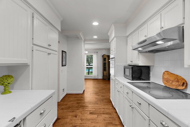 206 S Field St, Prosper, TX 75078 - kitchen with tile countertops, black appliances, under cabinet range hood, ornamental molding, and recessed lighting