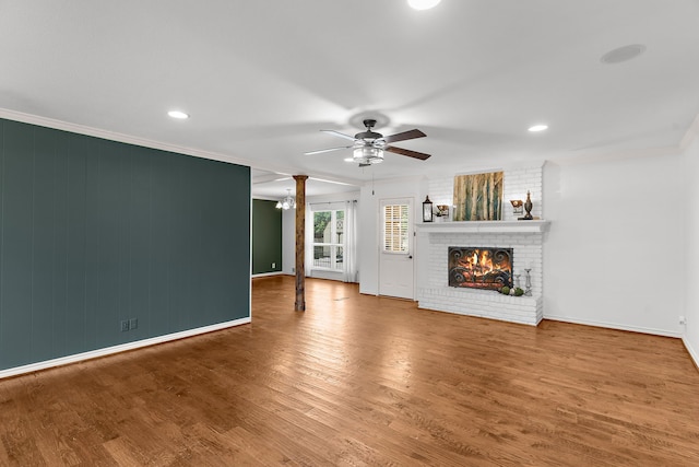 206 S Field St, Prosper, TX 75078 - unfurnished living room with ceiling fan, a fireplace, wood finished floors, crown molding, and decorative columns