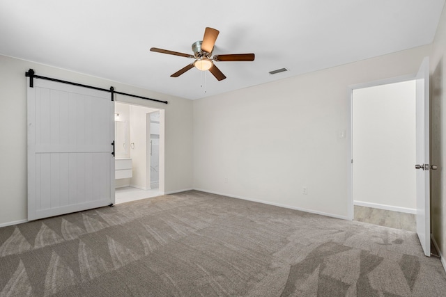 1828 Tracey Cir, Irving, TX 75060 - unfurnished bedroom with a barn door, carpet floors, ceiling fan, and connected bathroom