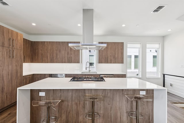4726 Manett St Unit 101, Dallas, TX 75204 - kitchen featuring modern cabinets, island exhaust hood, a large island, a kitchen breakfast bar, and recessed lighting