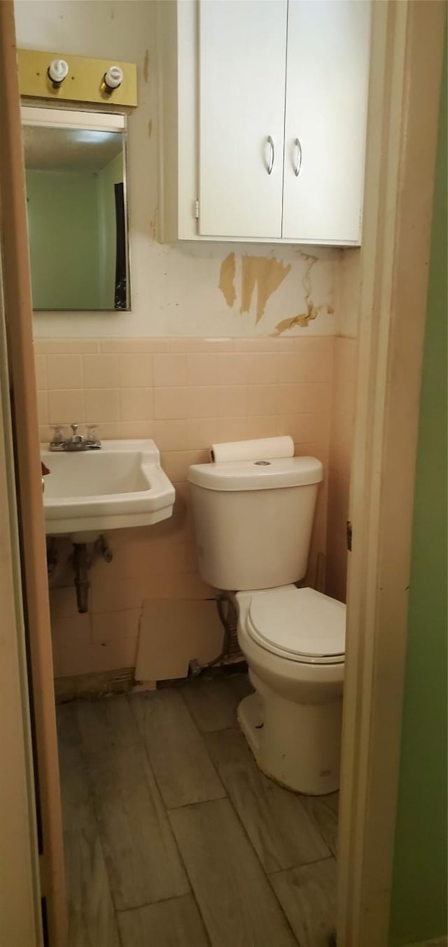 605 N Davis Dr, Arlington, TX 76012 - half bathroom featuring a wainscoted wall, tile walls, and wood finished floors
