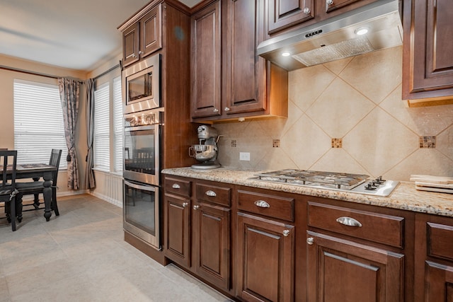 637 Grisham, Fate, TX 75087 - kitchen featuring under cabinet range hood, stainless steel appliances, tasteful backsplash, and light stone countertops
