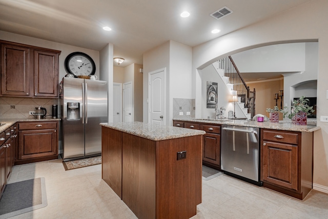 637 Grisham, Fate, TX 75087 - kitchen with stainless steel appliances, a center island, light stone countertops, arched walkways, and recessed lighting
