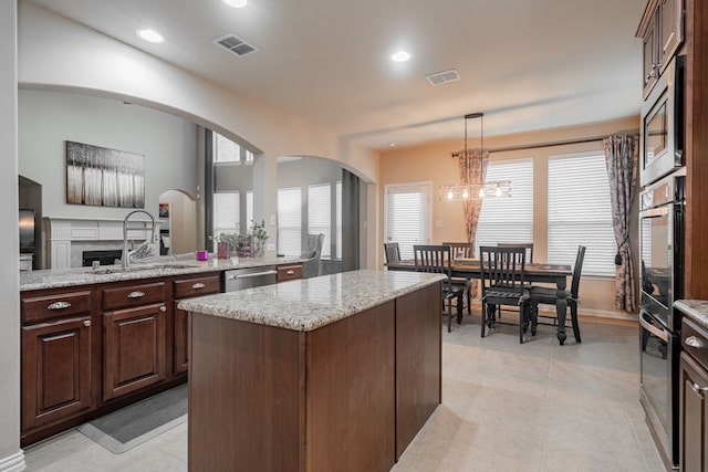 637 Grisham, Fate, TX 75087 - kitchen featuring appliances with stainless steel finishes, a center island, arched walkways, dark brown cabinets, and recessed lighting