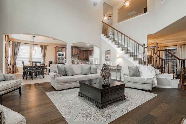 637 Grisham, Fate, TX 75087 - living room featuring arched walkways, stairway, a chandelier, dark wood-style floors, and a high ceiling