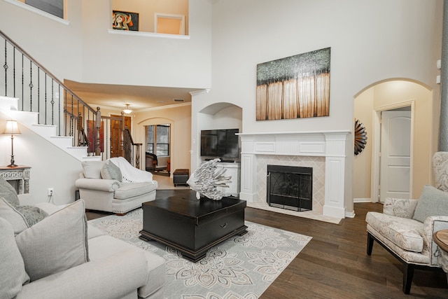 637 Grisham, Fate, TX 75087 - living area featuring a high ceiling, arched walkways, a tiled fireplace, wood finished floors, and stairway